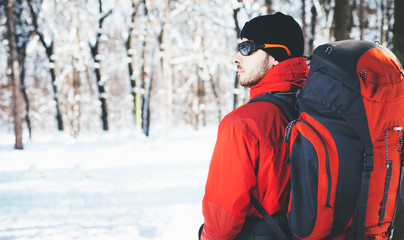 Fototapeta na wymiar Man hiking at winter mountain/Man hiker trekking in snow forest at winter mountain. Healthy lifestyle winter adventure
