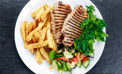 Grilled pork meat  with fried potatoes and vegetables