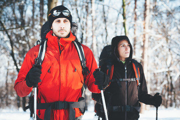 Man and woman hiking together/Man and woman couple hikers trekking in snow forest at winter mountain