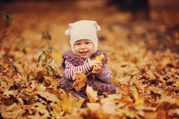 Девочка в шапочке держит листья и улыбается - obrazy, fototapety, plakaty