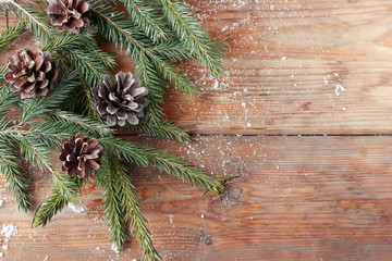 Winter background with fir-tree branches and cones on boards.