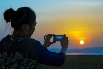 Young woman photographing sunset, Mandalay