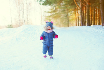 Fototapeta na wymiar Cheerful little child playing on snow in winter forest