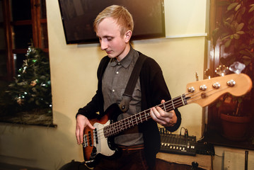 Obraz premium stylish bass guitarist playing on a concert on a background of h