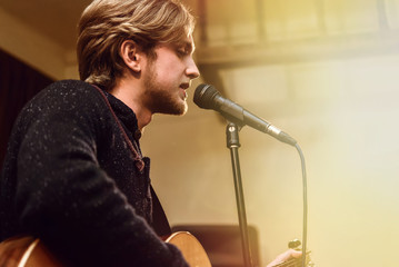 stylish vocalist with beard performing lyrical song on stage wit