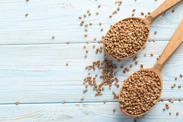 Buckwheat seeds in wooden spoon on a blue wooden table