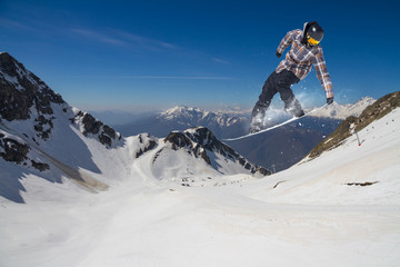 Flying snowboarder on mountains. Extreme sport.