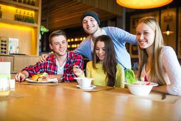Group of girls and boys eat at the cafe.