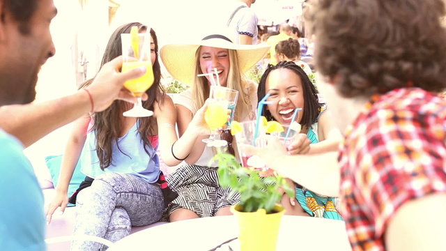 Three female friends drinking cocktails on terrace cafe in summer