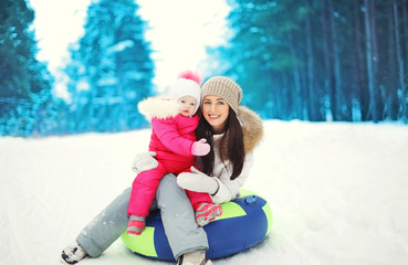 Obraz premium Happy mother and child sitting on sled in winter snowy day