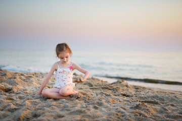 Fototapeta na wymiar Cute little girl having fun with the sand