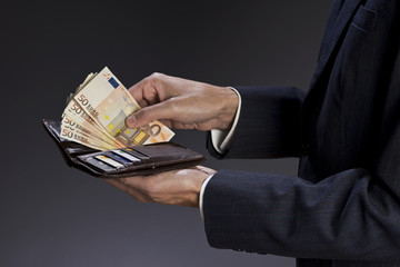 Businessman hands holding wallet with credit cards and stack of money, euro bills. Fifty euros banknotes, isolated gray background.
