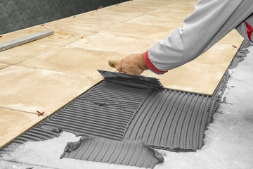 Home improvement, renovation - construction worker tiler is tiling, ceramic tile floor adhesive - obrazy, fototapety, plakaty