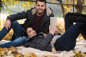 Happy Couple With Tablet Computer In The Park