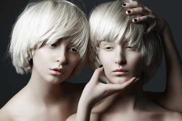 Portrait of two beautiful girls twins with closed eyes in studio, closeup