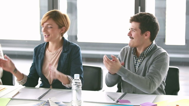 Colleagues giving high-five and applauding in conference room 