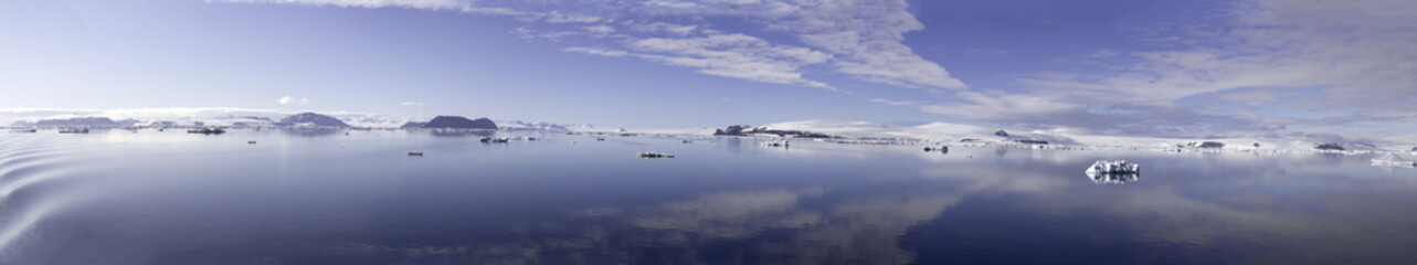Clouds reflecting in calm seas of Antarctic Sound on sunny day.