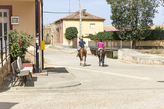 people riding horses on a town street