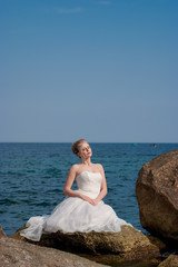 Fototapeta na wymiar Young beautiful bride, at the stone, in white veil wedding dress