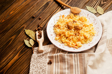 
national cuisine , stewed rice with meat , which is called pilaf with bay leaf and pepper on a wooden background 