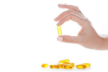 Soft gels pills with Omega-3 oil in fingers closeup on white