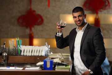 Handsome young man toasting with wine at the bar
