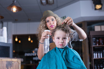 Young woman spraying boy hair