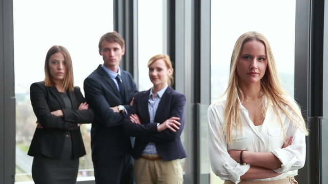 Portrait of attractive blonde businesswoman, colleagues in background