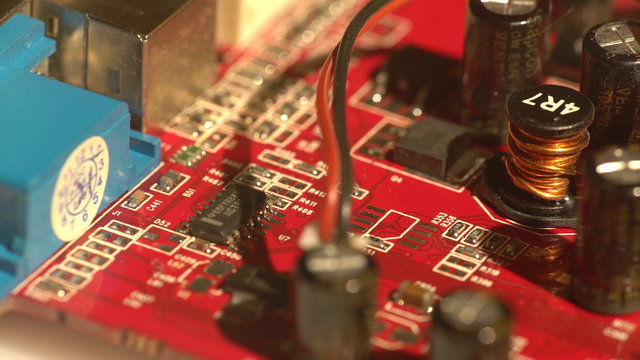 View of capacitors and other electronic elements on a red circuit board
