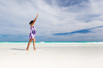 Pregnant woman walking on white beach