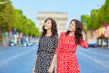 Naklejka premium Beautiful twin sisters in front of Arc de Triomphe