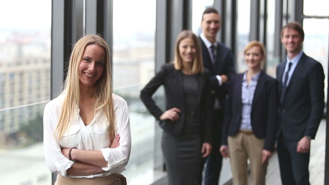 Portrait of attractive businesswoman smiling, colleagues in background