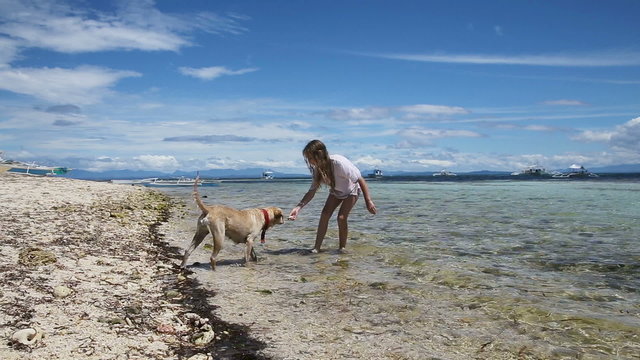 Young girl and dog playing in the water, the sea on a tropical beach.Happy girl playing with her dog in water.Travel concept.Family,summer vacation.