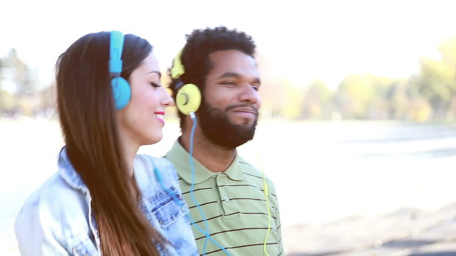 Happy couple with headphones listening to music and dancing 