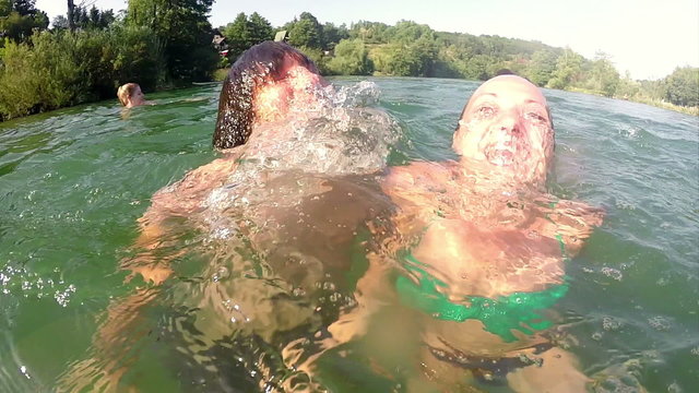 Two young friends subdiving under the water and similing into camera