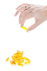 Soft gels pills with Omega-3 oil in fingers closeup on white