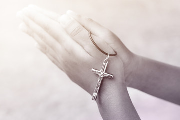 Hand with a rosary against gray background, religious concept.process in vintage color tone