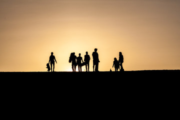 Fototapeta na wymiar Silhouettes of sand boarders during the sunset near desert oasis Huacachina near Ica, Peru