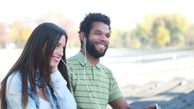 Young couple sharing earphones while listening to music