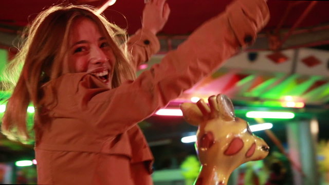 Beautiful woman having fun riding carousel in amusement park