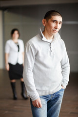 Fototapeta premium Middle aged man in casual clothes with short hair thoughtfully looking directly into camera, the employee gets job. In background, HR Director woman wearing white suit and strict black dress waits.