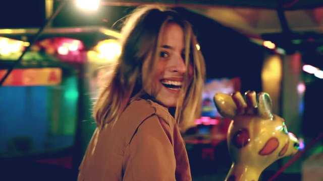 Beautiful woman having fun riding carousel in amusement park