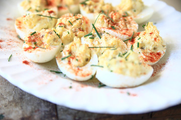 Deviled eggs with smoked paprika and chives on a white fluted platter
