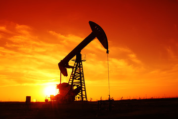 Oil field scene, the evening of beam pumping unit in silhouette