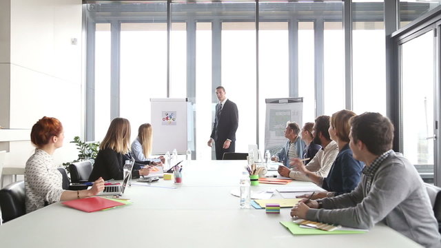 Handsome director pointing at flipchart during a meeting 