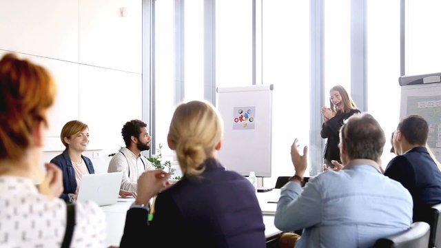 Colleagues applauding to beautiful businesswoman after presentation