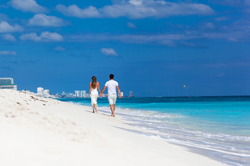 Young beautiful newlyweds on white sandy beach, rear view