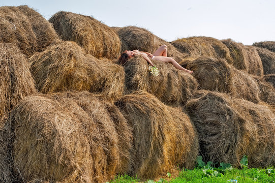 Attractive nude woman relaxes on hay
