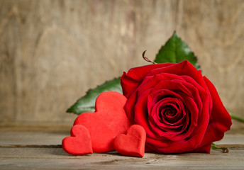 Beautiful rose and three handmade hearts  on the wooden board su