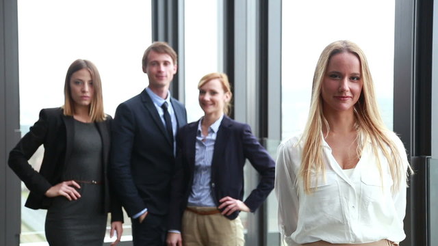 Portrait of attractive blonde businesswoman smiling, colleagues in background